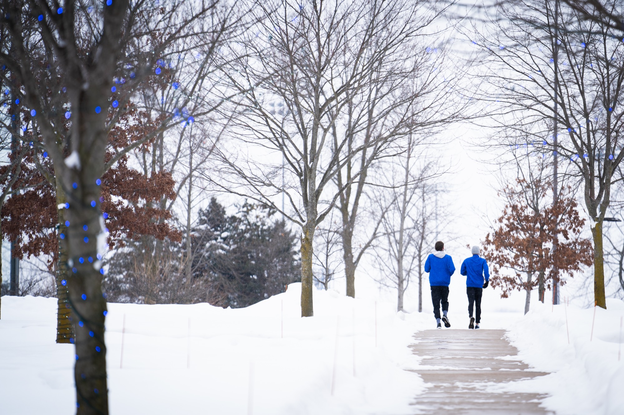 students running on campus on a snowy day